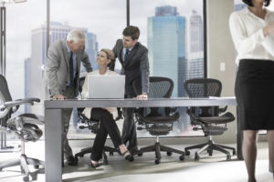 A group of businesspeople at a laptop discussing a project