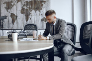 Man in a business suit writing on pad of paper