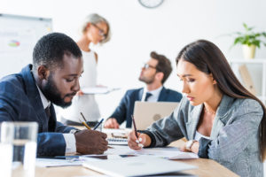 side view of young multicultural businesspeople writing something in office