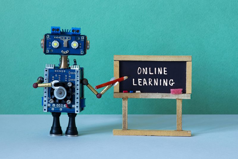 Online learning and distance education concept. Abstract interior classroom. Black chalkboard with handwritten text Online Learning. Robot teacher with a pencil pointer